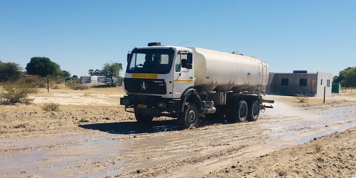 A tanker sprays water to reduce the dust on a road.